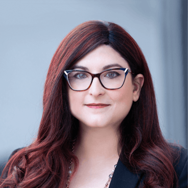 a woman wearing glasses and smiling at the camera