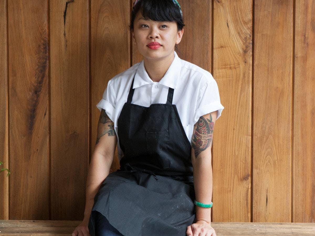 a woman chef standing against a wooden wall