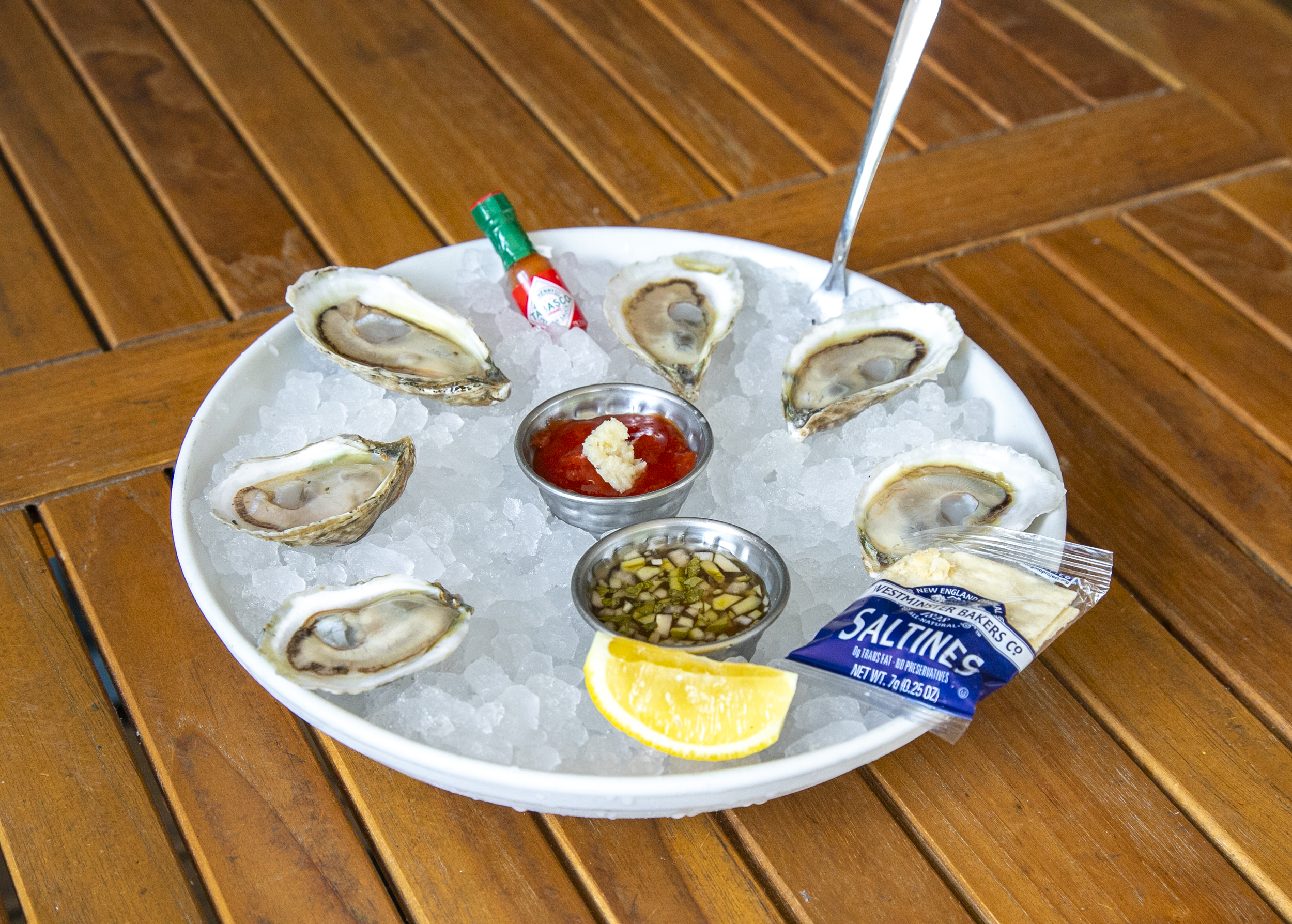 a plate of oysters on ice with sauces and lemon
