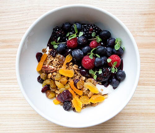 a bowl of fruit and seeds on a wooden table