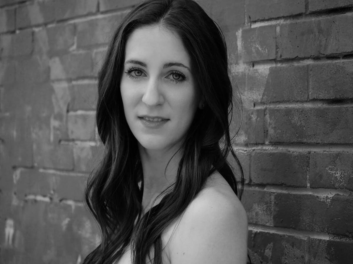 a woman standing in front of a brick wall