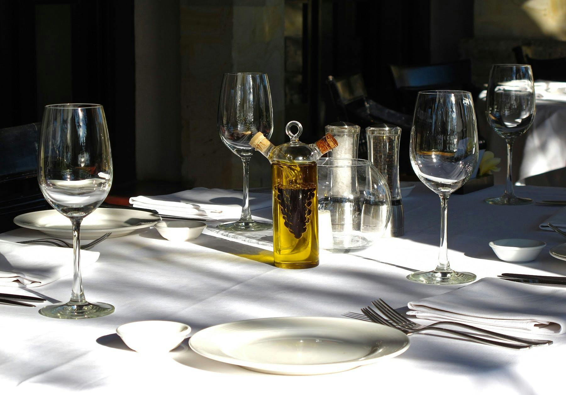 two glasses of wine served on a white table, which has cutlery on it