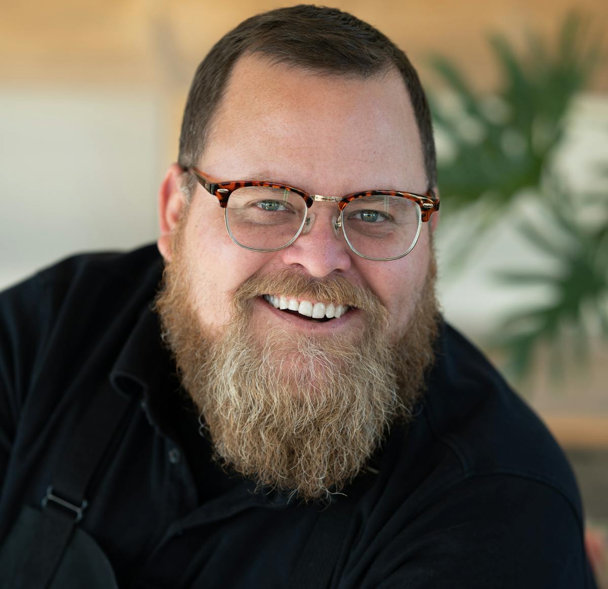 a man wearing glasses and smiling at the camera