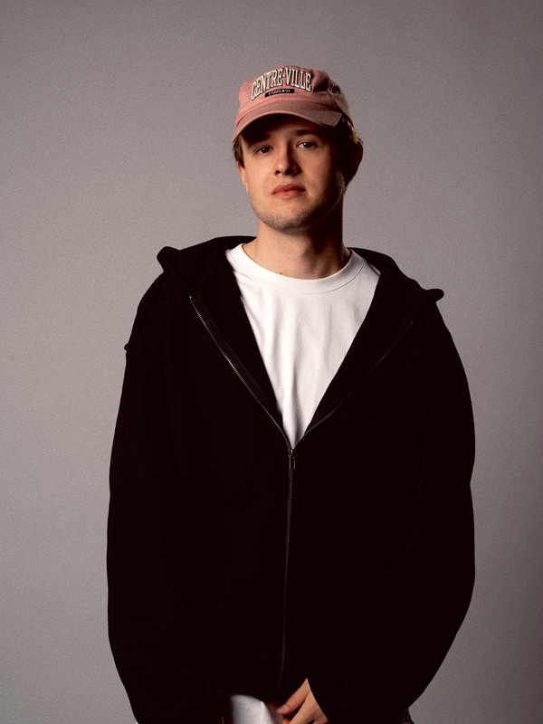Studio portrait of a man in a pink hat and black hoodie