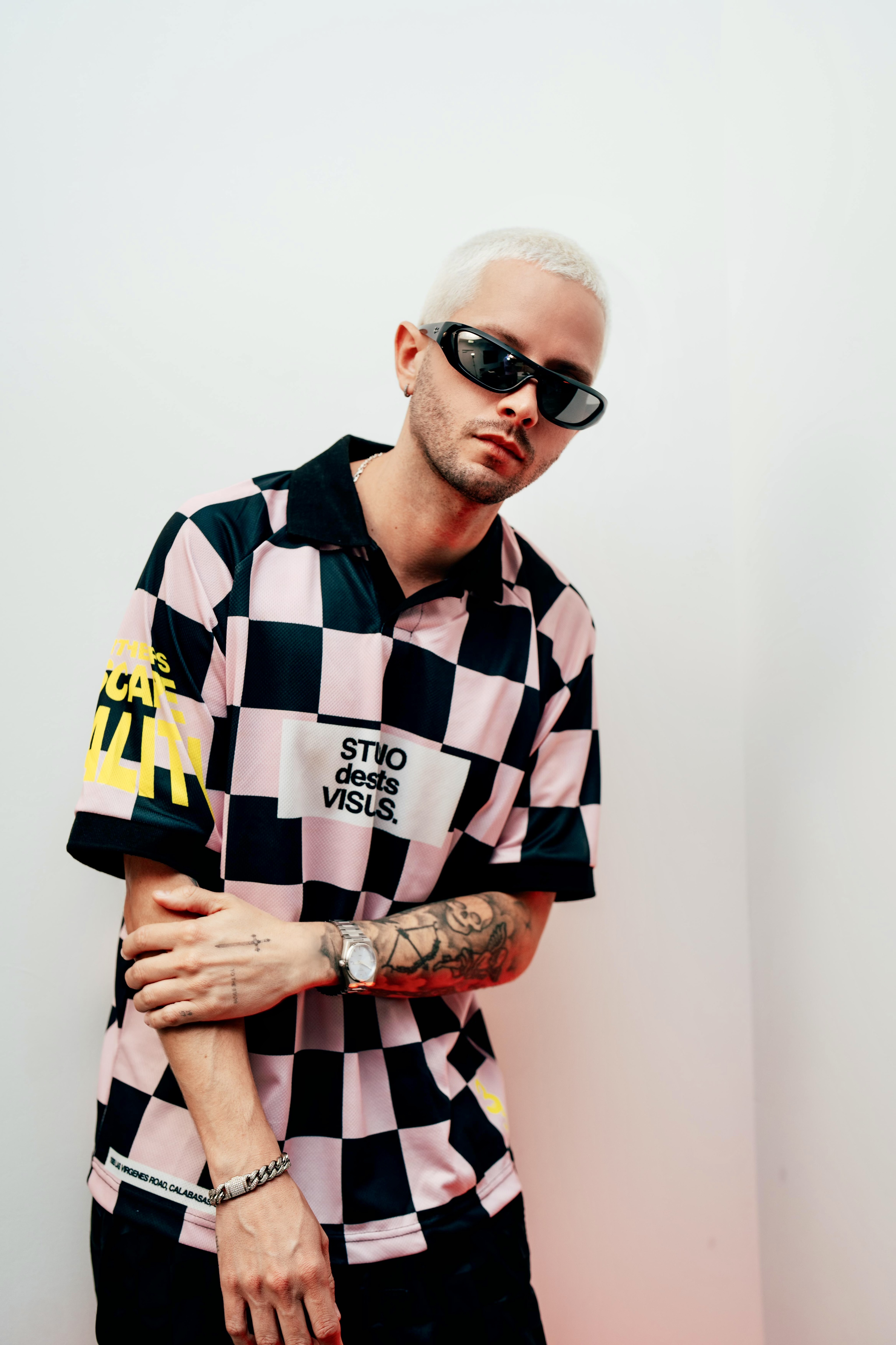 Studio portrait of a man in a checkered jersey and sunglasses against a white background