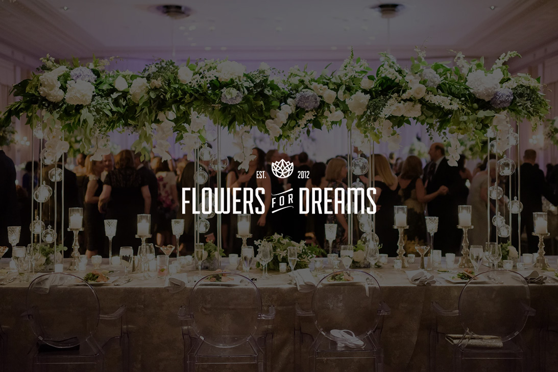 Flowers for Dreams logo over an elegantly set reception table with tall white flowers