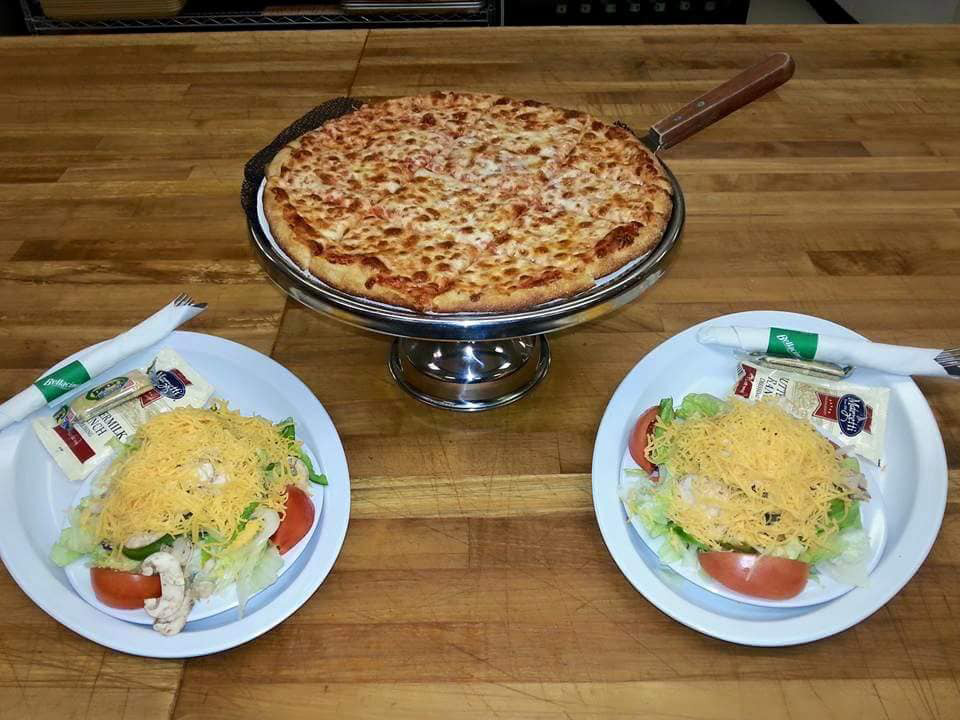 a pizza on a plate with salad on a table