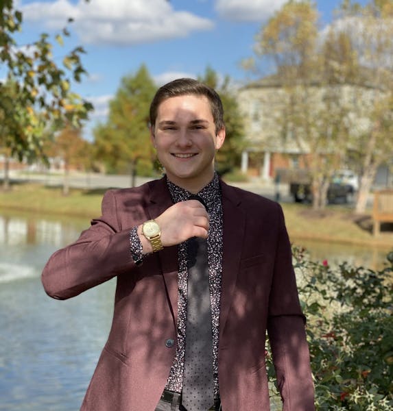 a man wearing a suit and tie standing next to a body of water