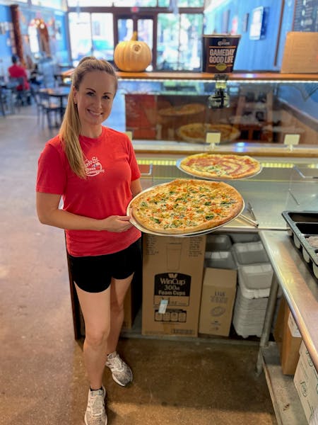 a woman standing in front of a pizza