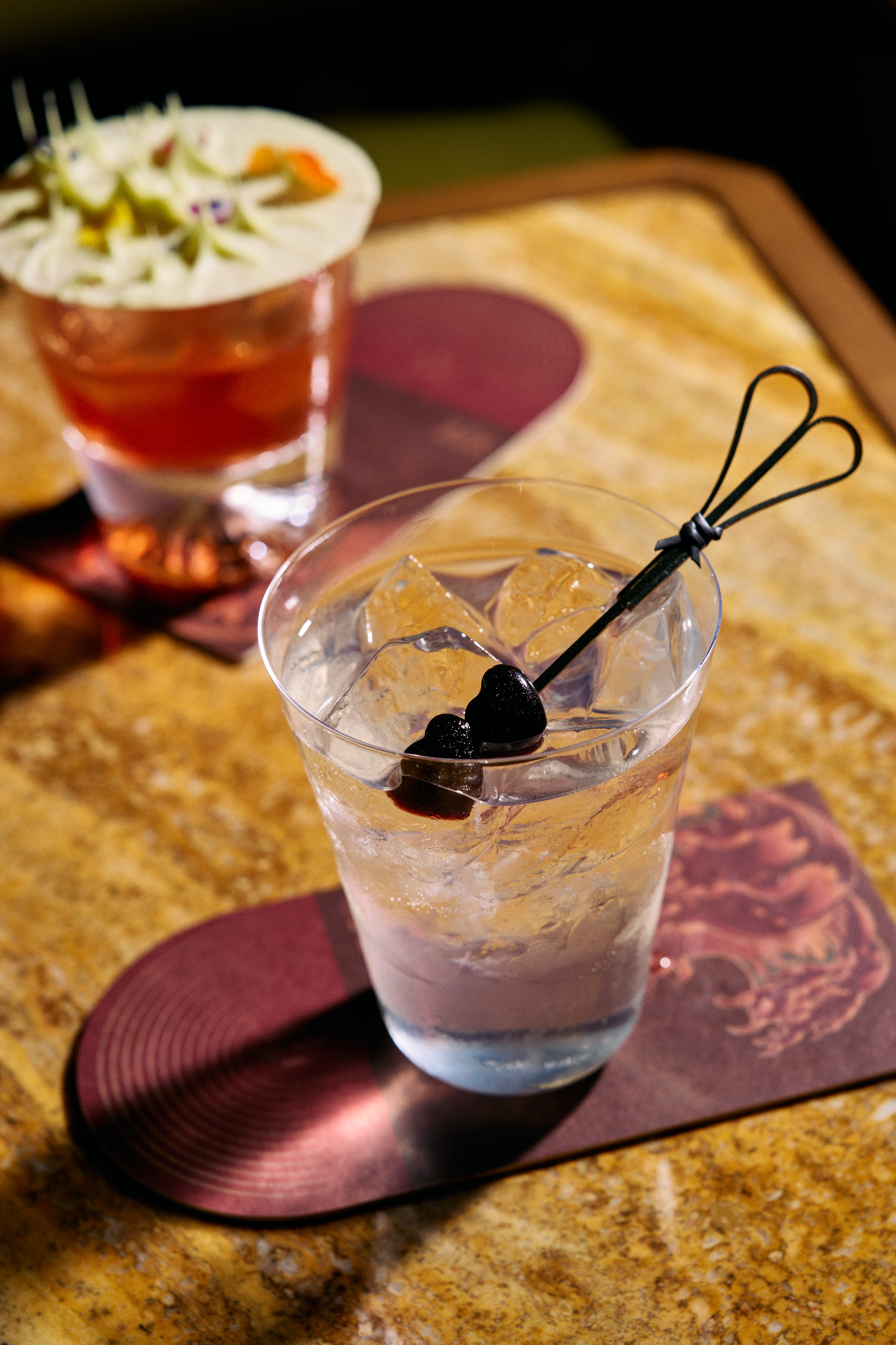 a glass with ice and a drink with a black object on top