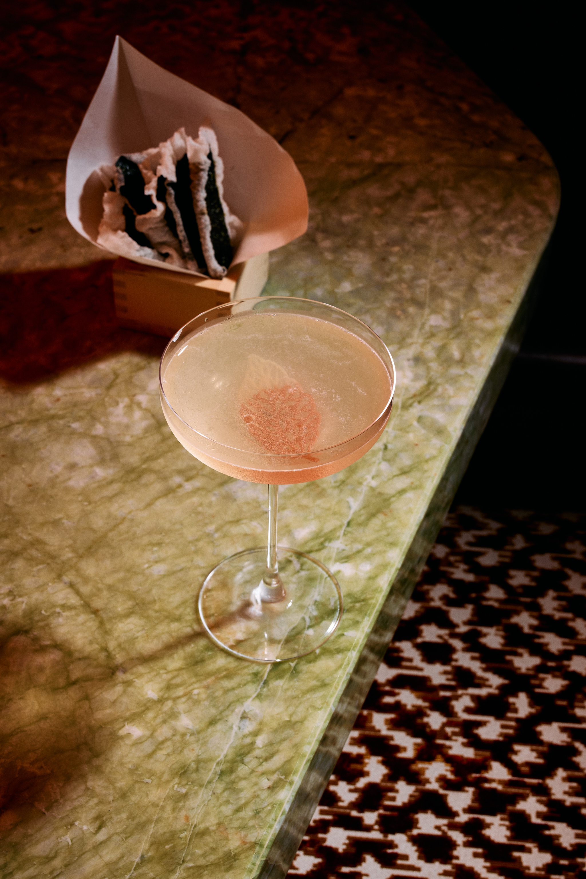 a glass of pink liquid on a marbled counter