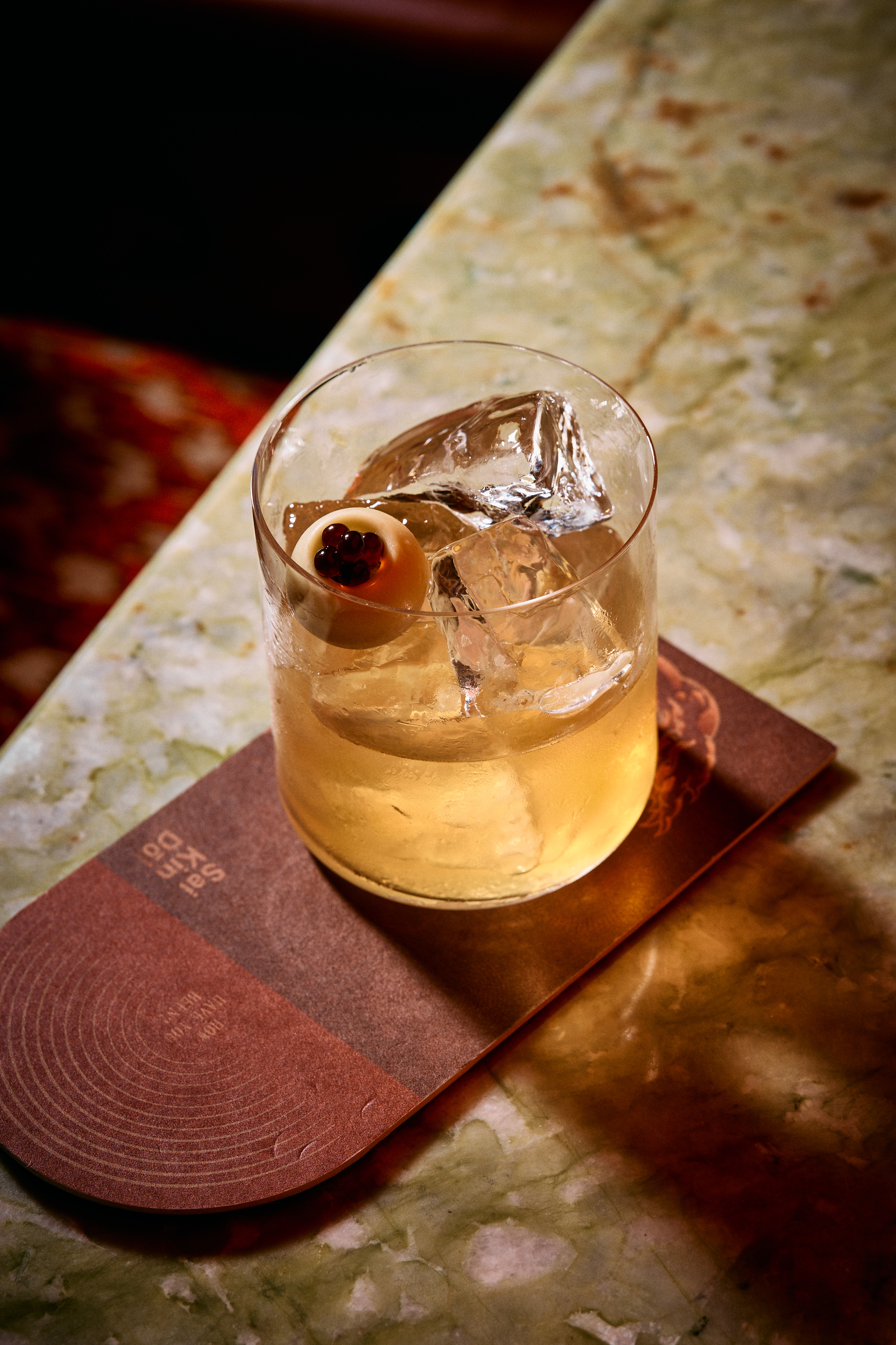 a glass of liquid with ice and a ball on top of it