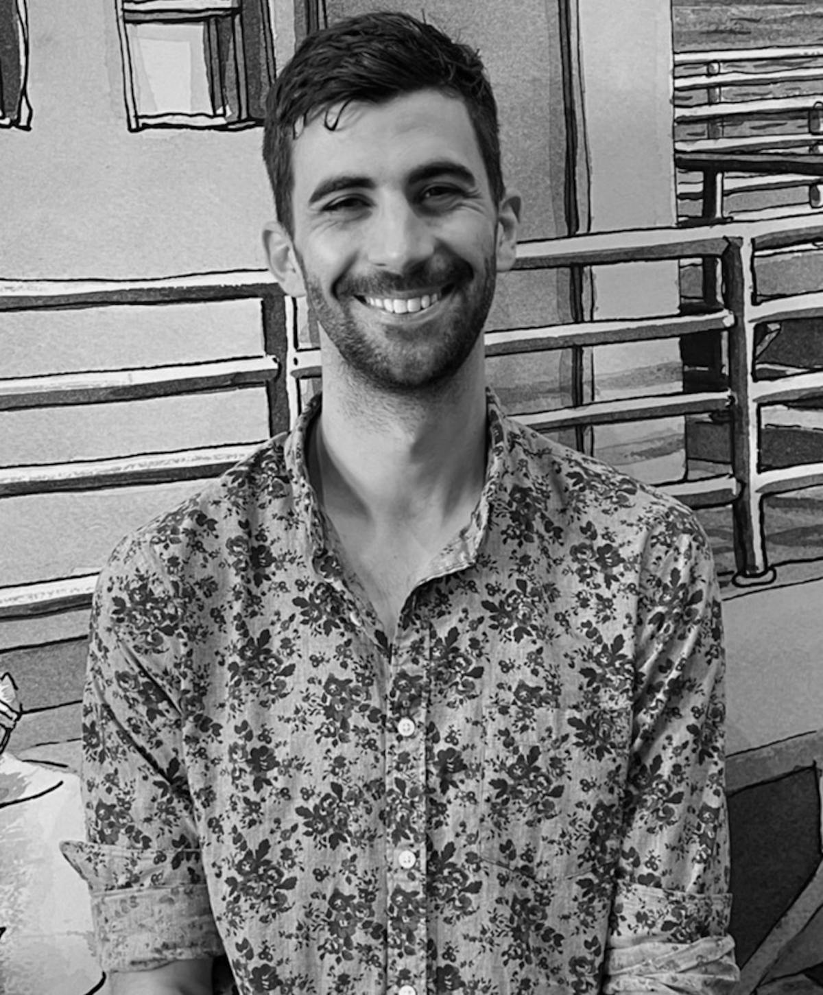 A man wearing a patterned shirt smiling in front of the camera