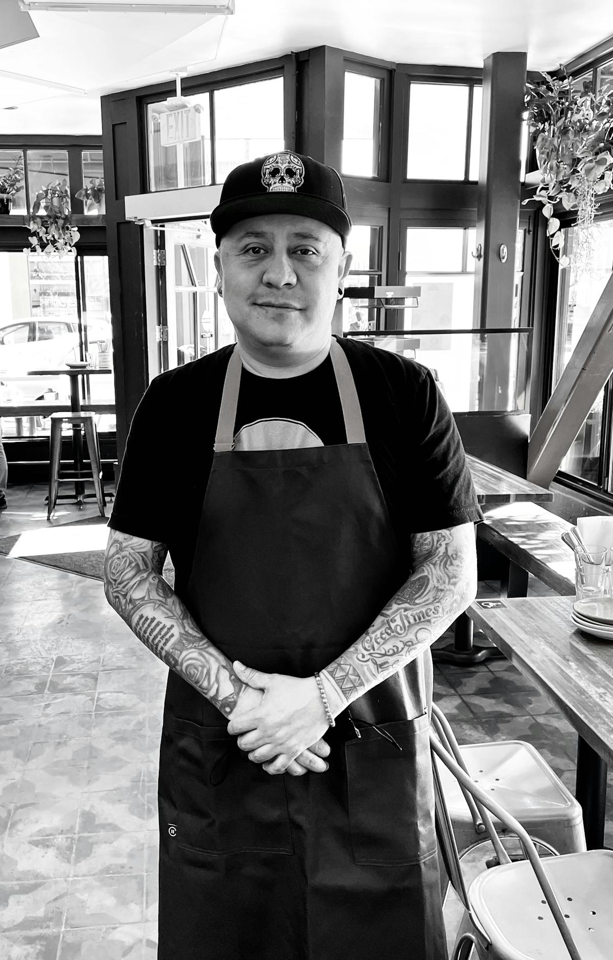 A man wearing a cap and apron posing in front of the camera
