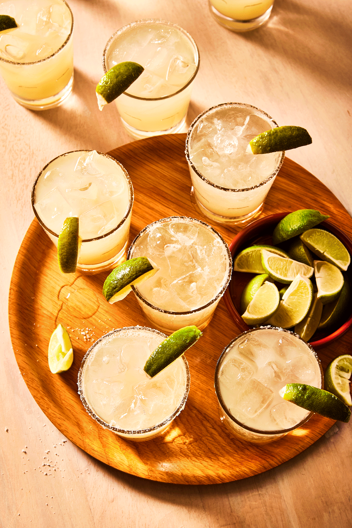 A tray of margaritas garnished with lime and lemon wedges