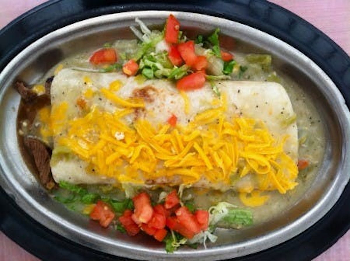 Steak burrito with shredded cheese and vegetable toppings