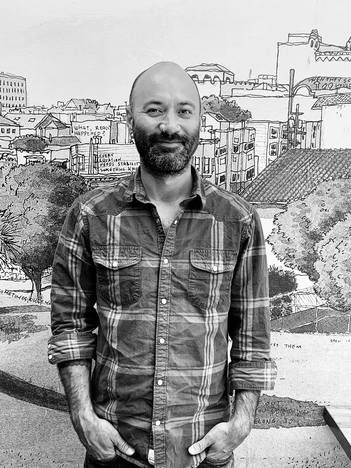 A bearded man in a plaid shirt smiling in front of the camera