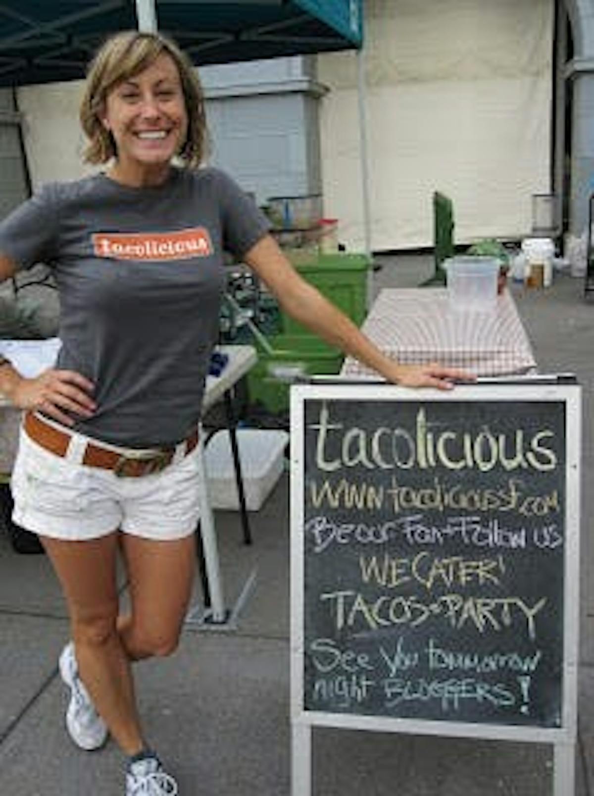 kelly posing beside a tacolicious sign