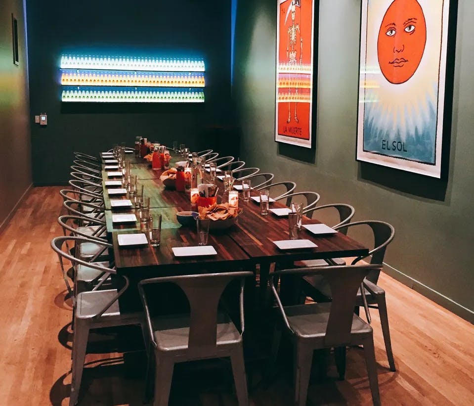 high-ceilinged private room is adorned with Paul Madonna artwork, a backlit display of Jarritos bottles and walls are painted our signature Tacolicious teal