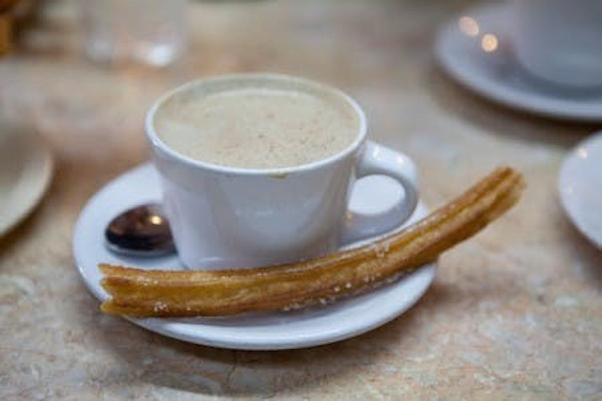 a coffee and a large churro with dipping caramel