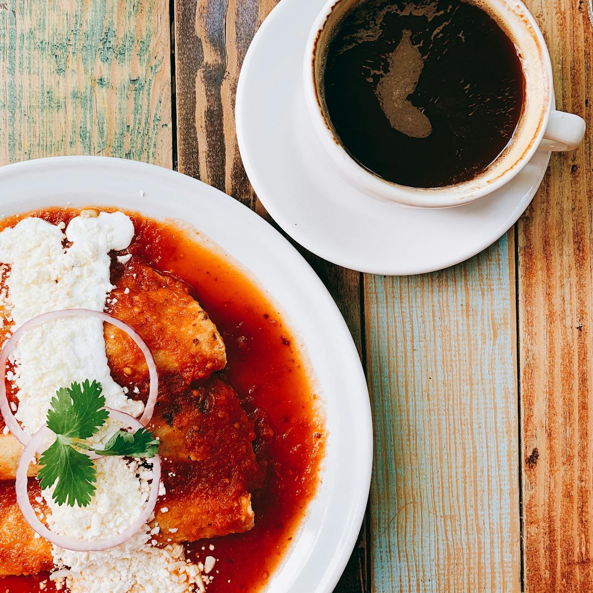 a plate of taco flautas with a coffe on the side and parm cheese on top