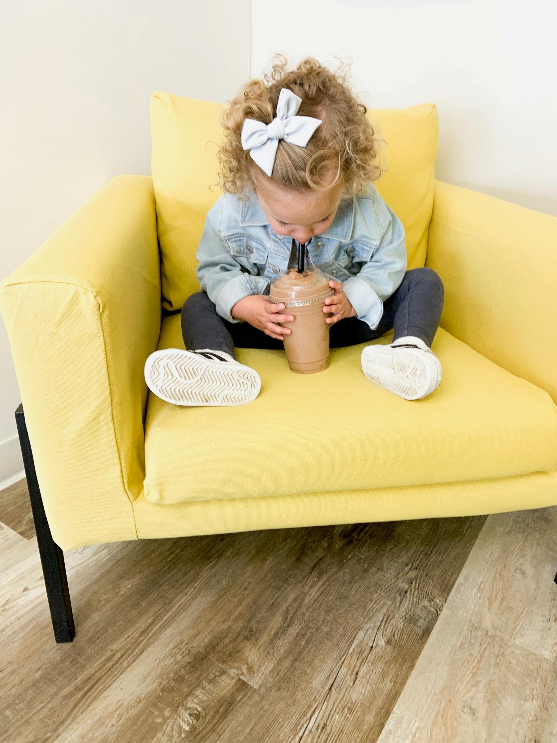 a baby sitting on a sofa with a smoothie