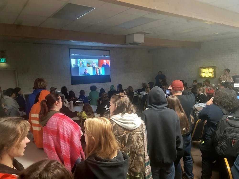A diverse crowd of people seated in a dimly lit room, attentively watching a movie on a large screen