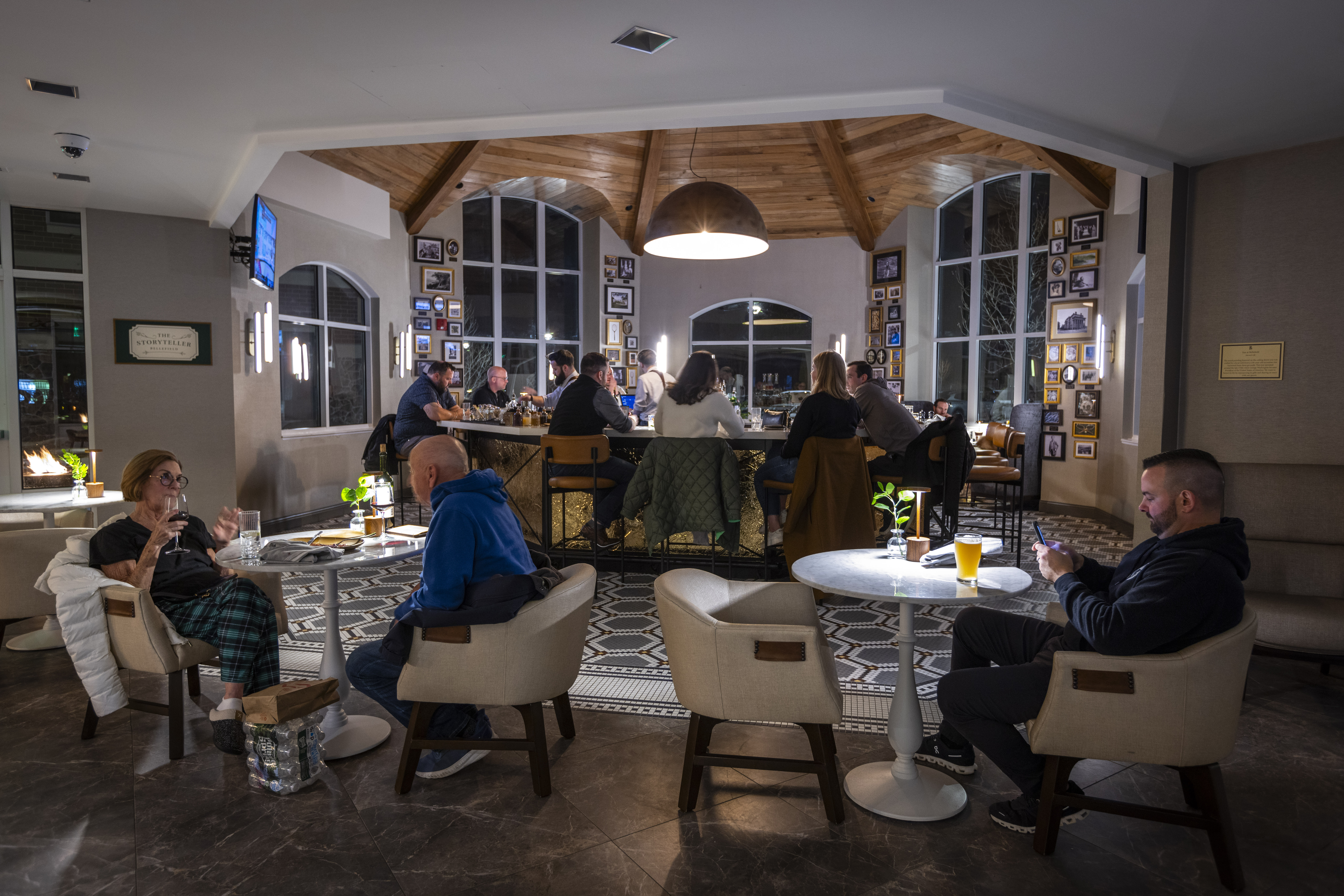 a group of people sitting at tables in a room with a large bar