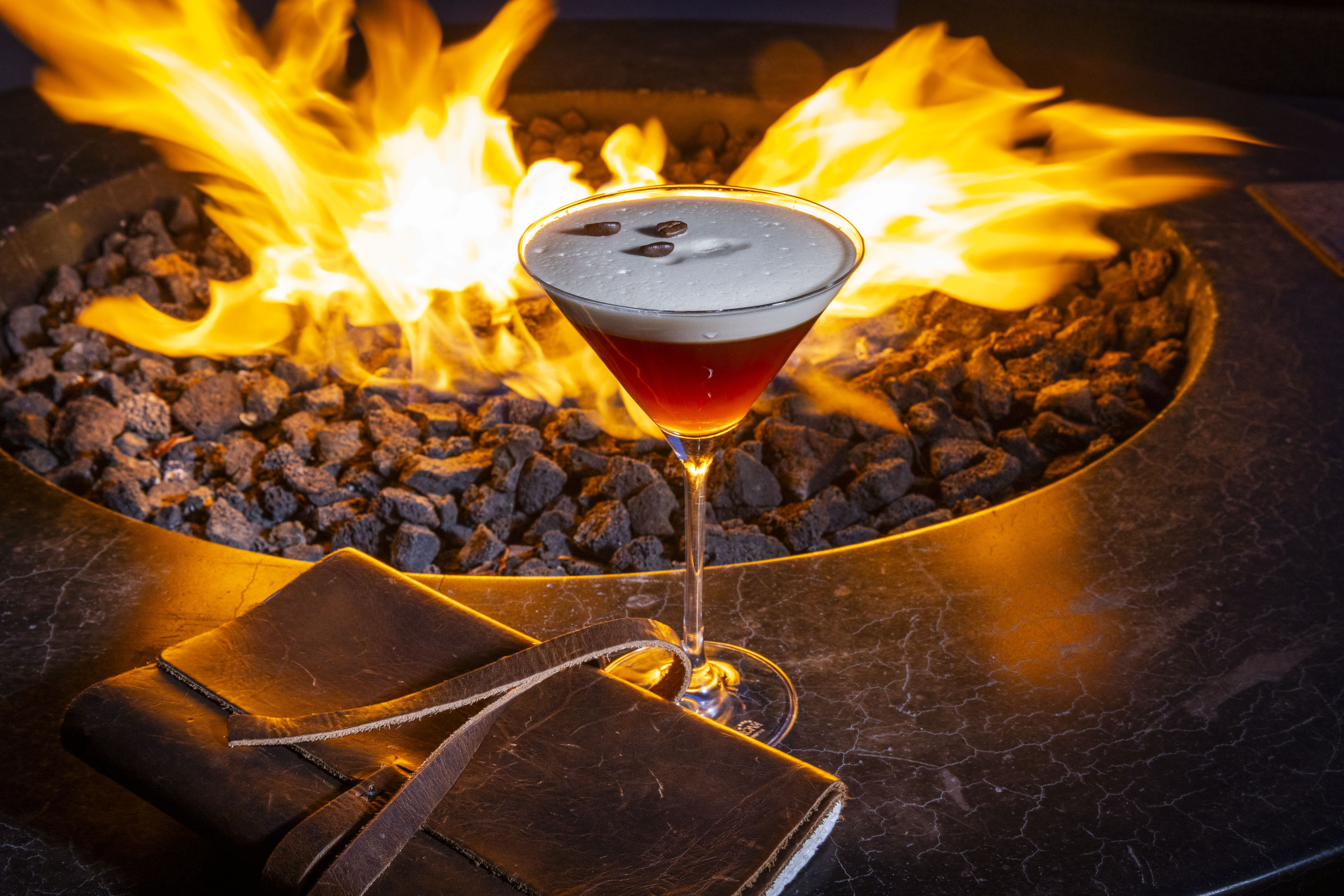 a glass of drink with a fire in the background
