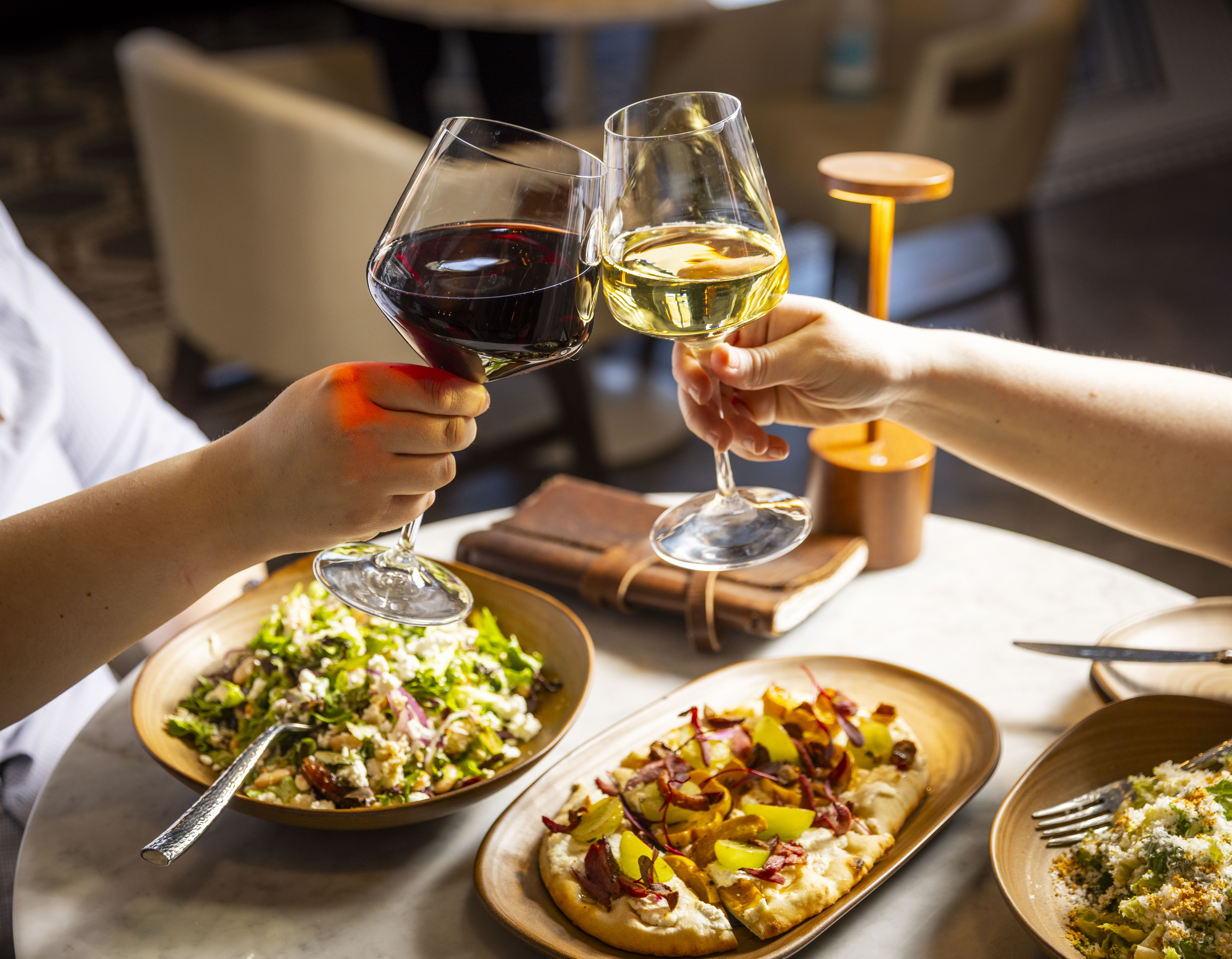 a couple of people holding wine glasses and a plate of food