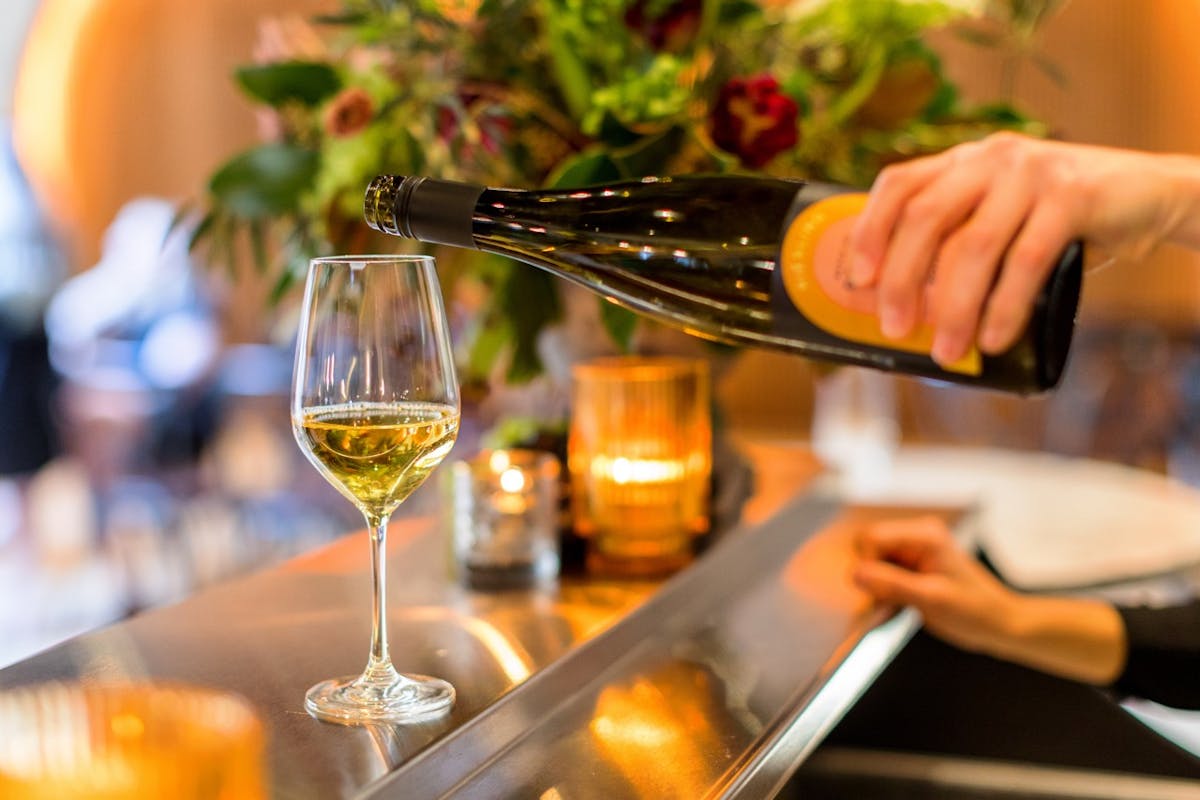 a person sitting at a table with wine glasses