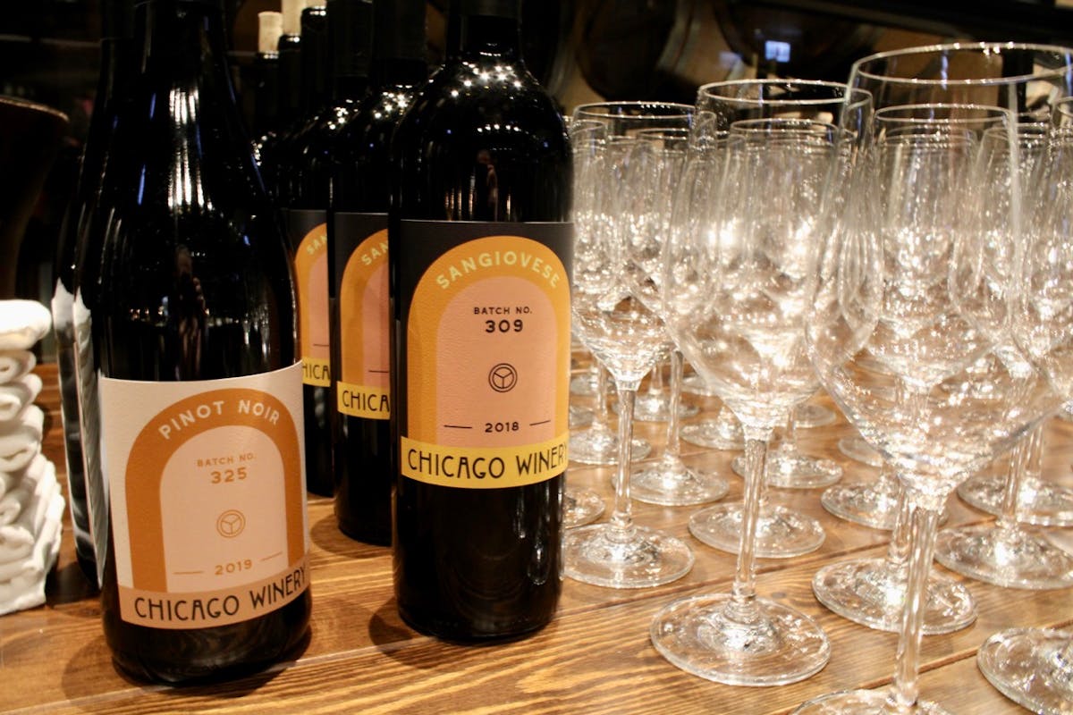 an empty bottle sitting on top of a table filled with wine glasses