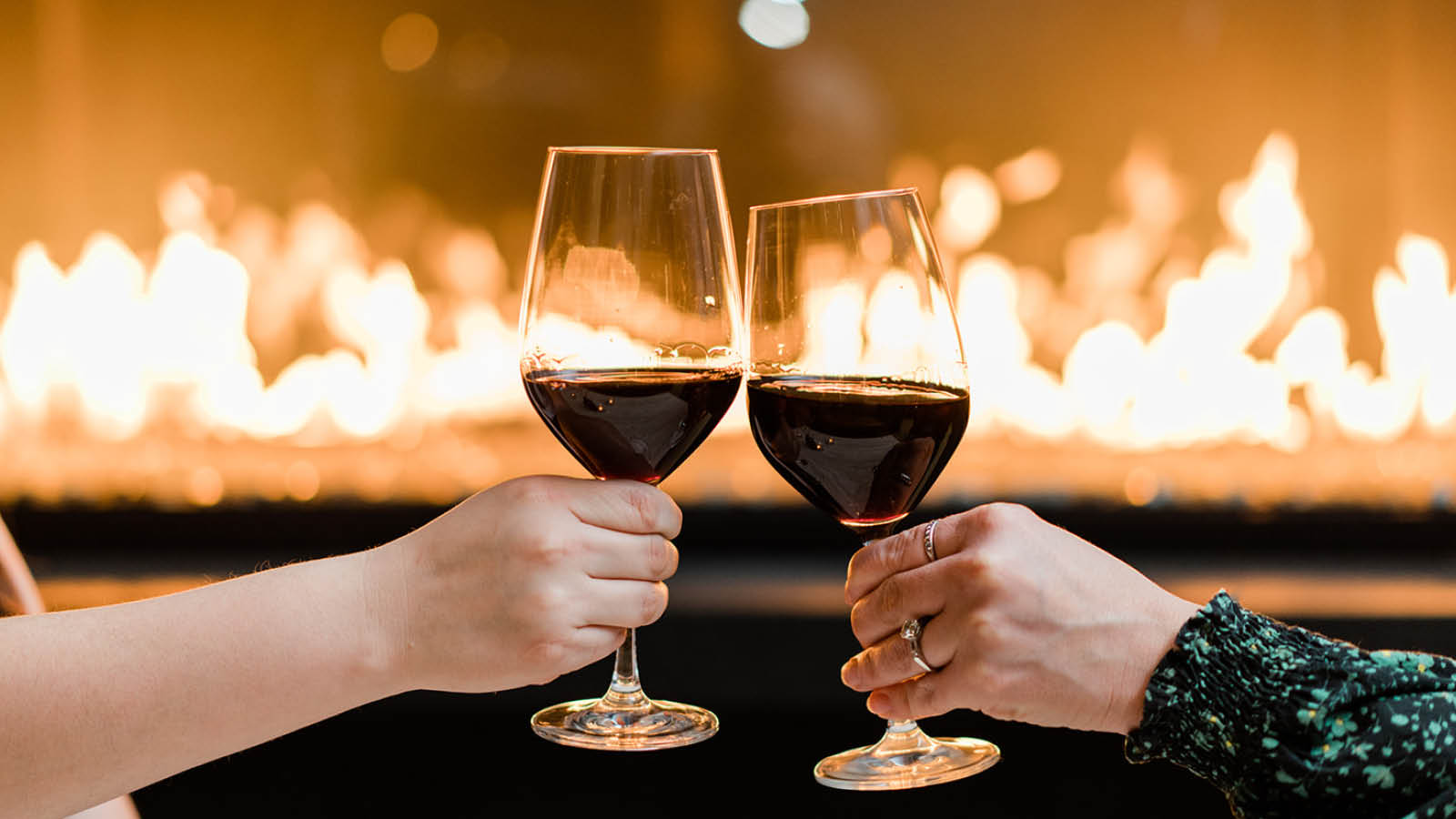 wo guests share a toast in the Chicago Winery private event space with a cozy roaring fire in the background.