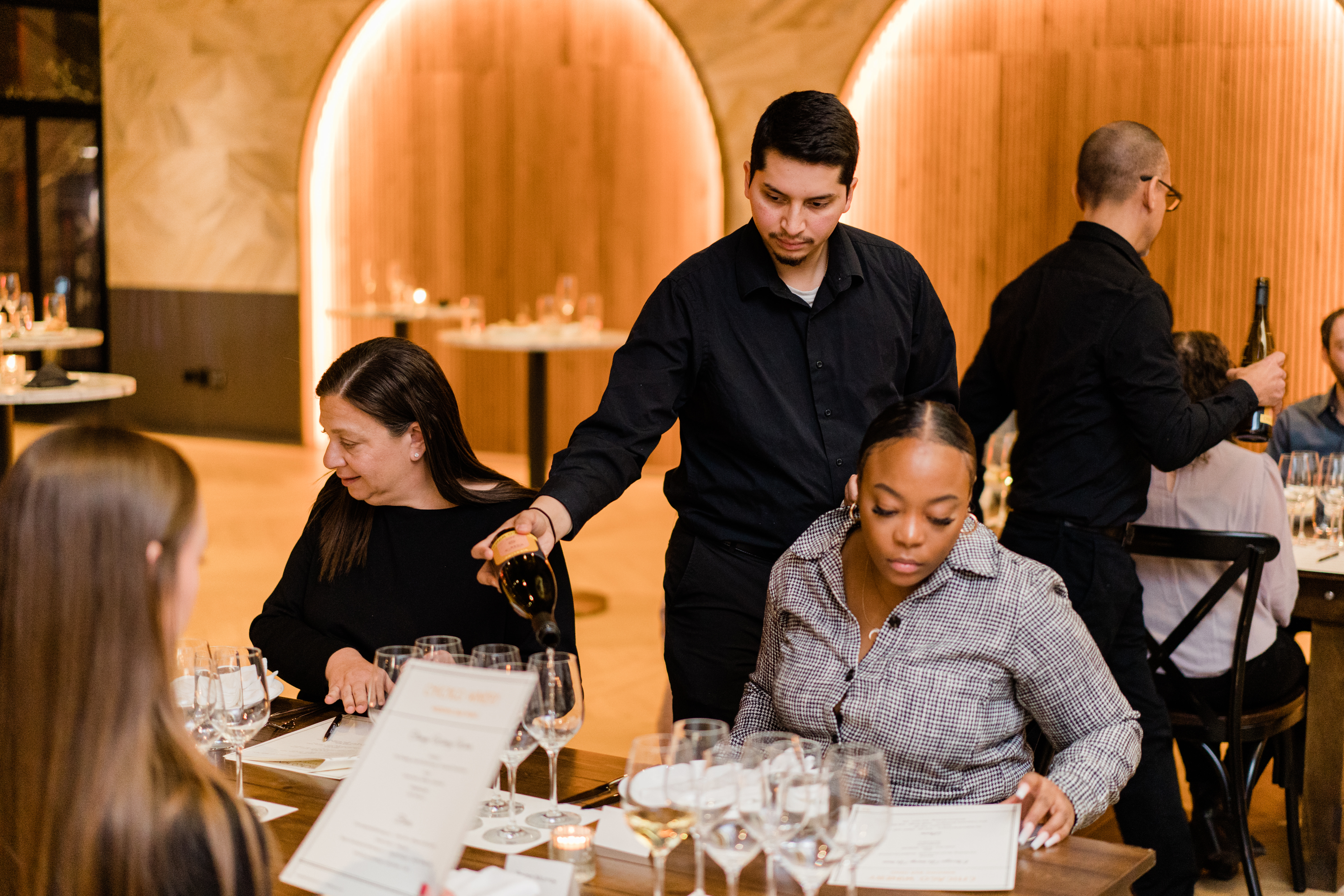 Group of guests being served wine at a winery birthday party.