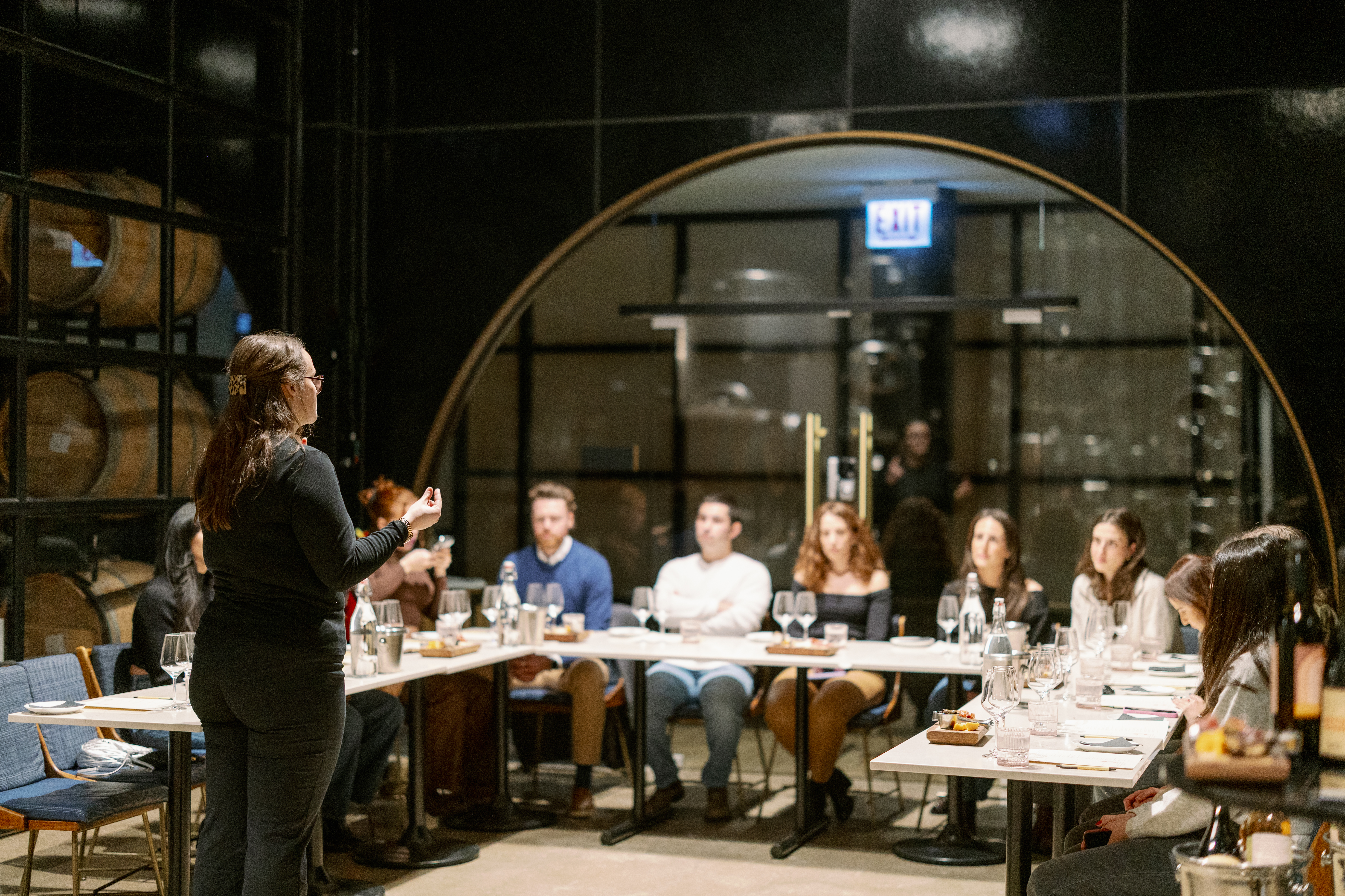 a woman standing in front of a group of people sitting at tables