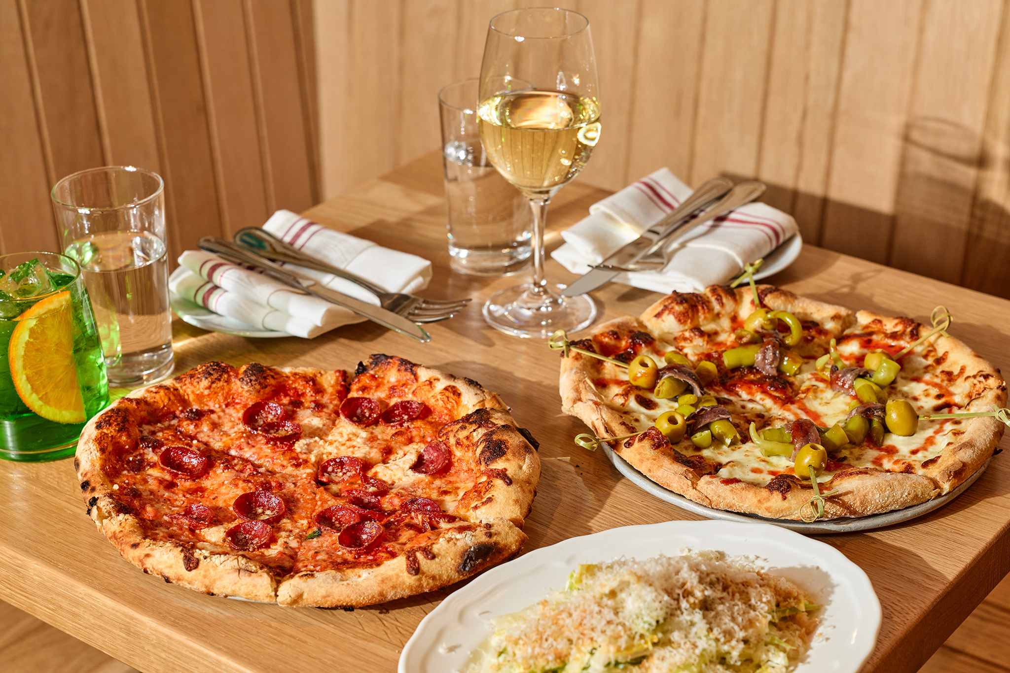 a table with pizzas and wine glasses