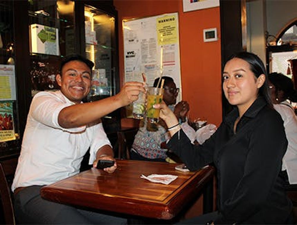 Man and woman raising glasses and smiling at our Greenwich Village, Manhattan Happy Hour restaurant.