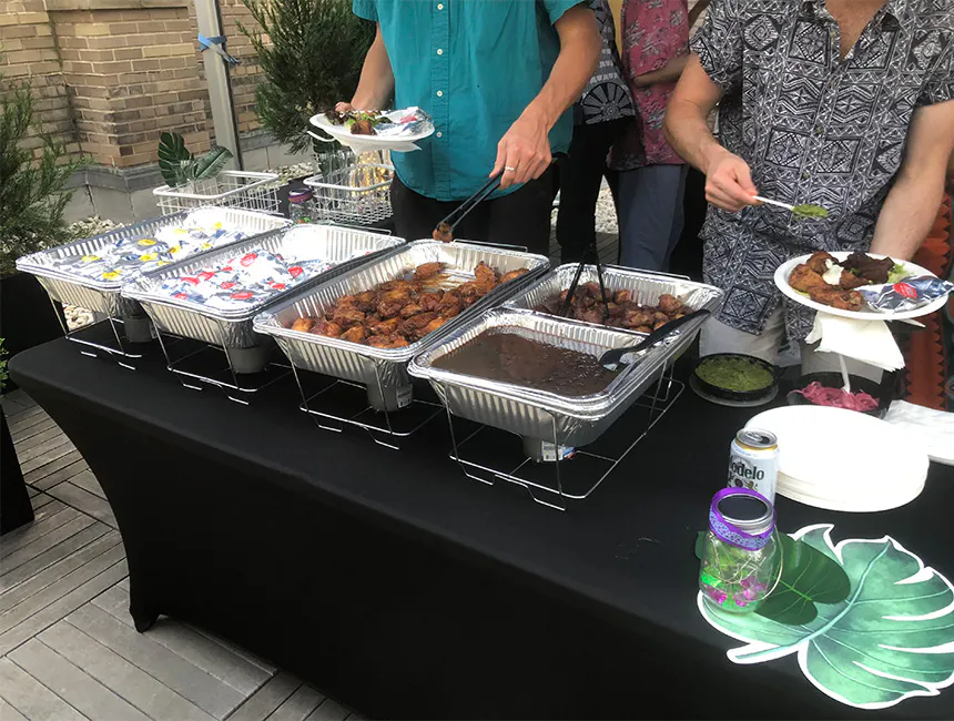 Employees taking chicken and beans from food trays provided by our Garden City South company event caterers.