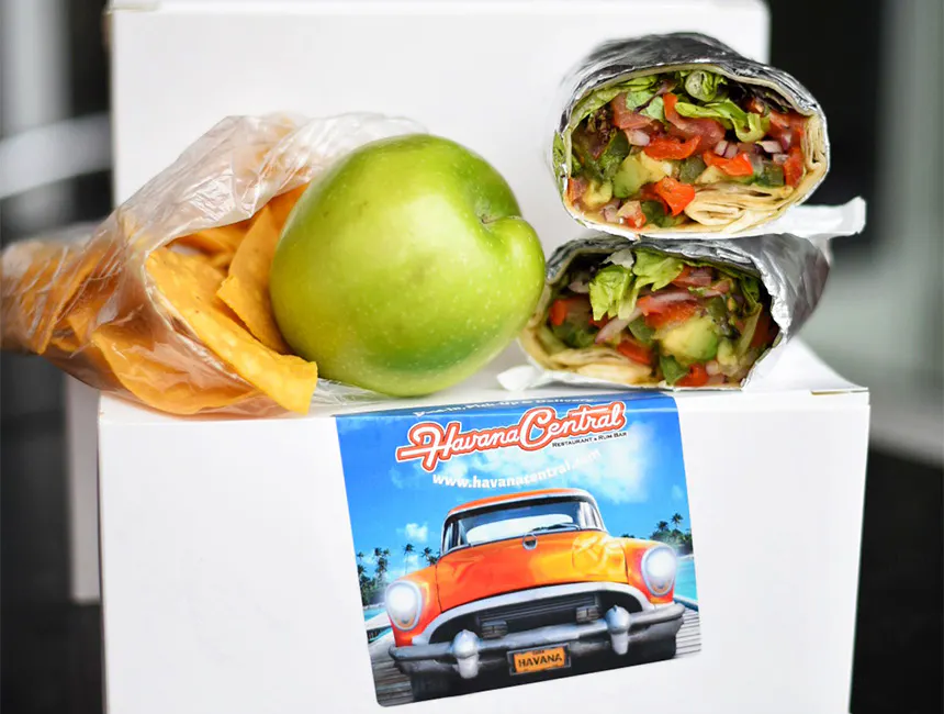 A boxed lunch consisting of a wrap, green apple, and chips, provided as part of our office party catering near Mineola, New York.