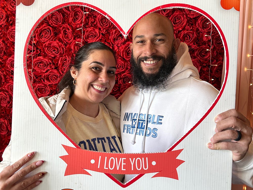 Woman and man posing behind a heart-shaped cutout at our Carle Place event space.