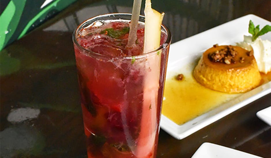 A cocktail next to a flan dessert plate, available at our Diamond District, Manhattan, NYC Thanksgiving restaurant.