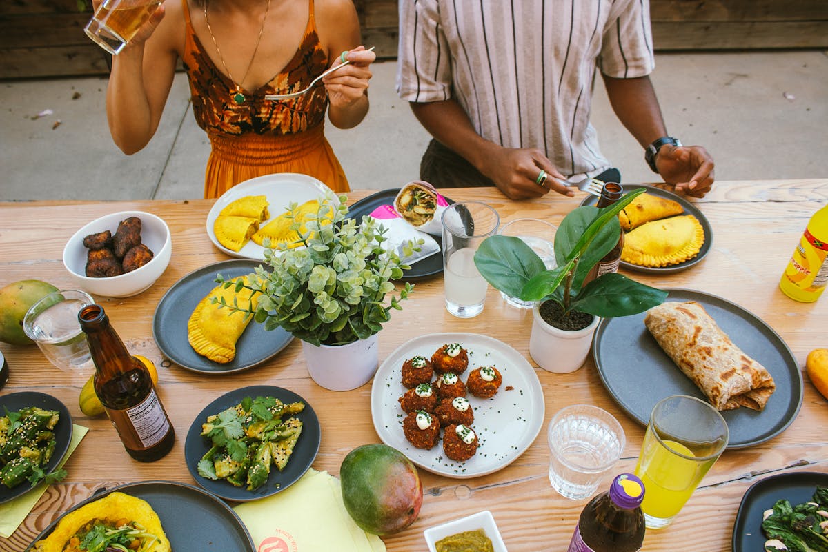 a person holding a plate of food on a table