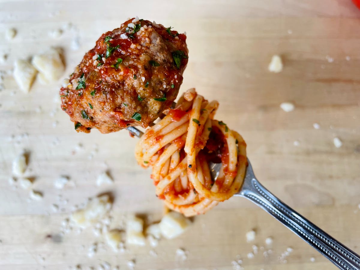 close up of a meatball with spaghetti swirled on a fork