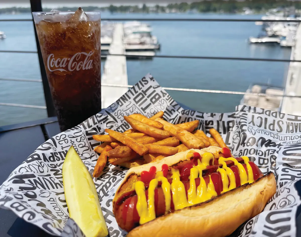 a hot dog and fries on a table with a drink