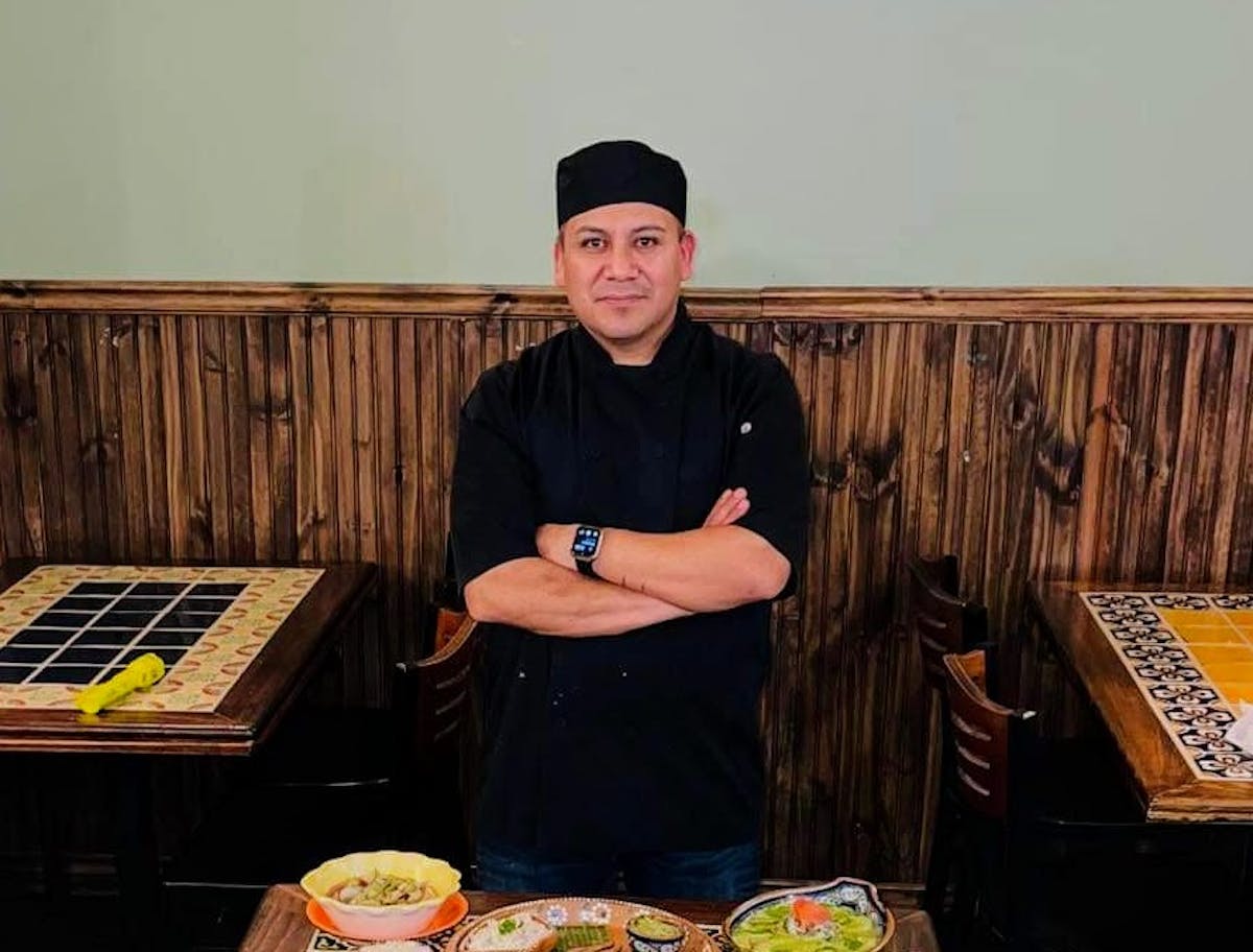 a man sitting at a table smiling for the camera