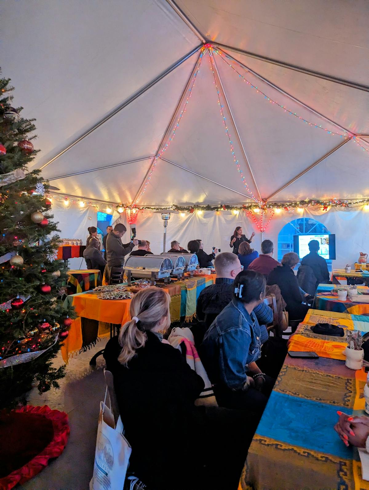 a group of people sitting at a table with an orange umbrella