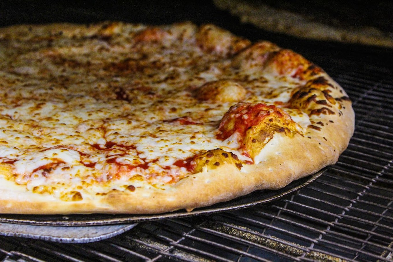 a pizza sitting on top of a metal pan on a grill