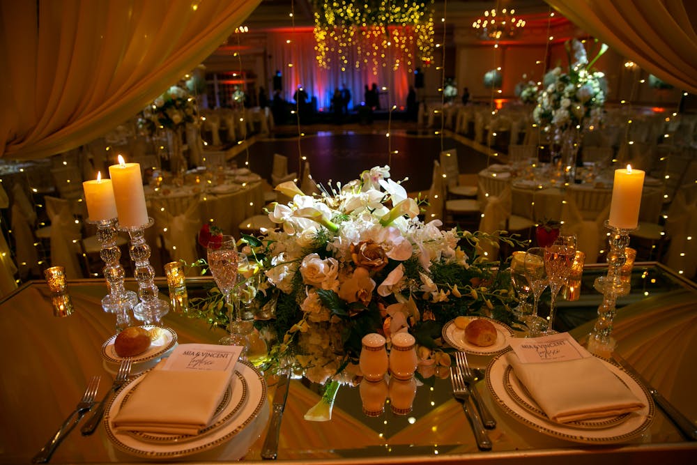 a vase of flowers on a table with wine glasses