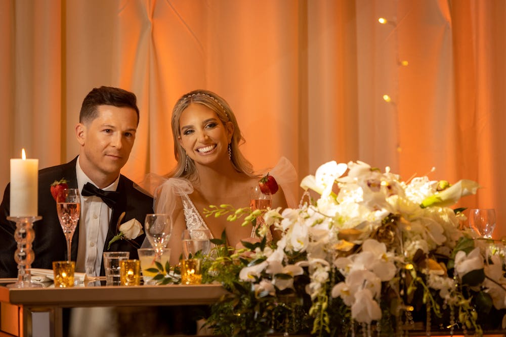 a man and a woman sitting at a table with a vase of flowers