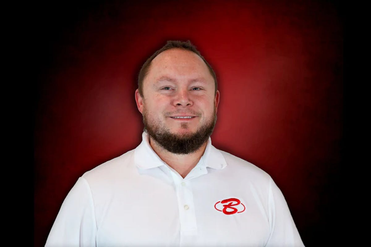 A man wearing a white shirt stands against a vibrant red background